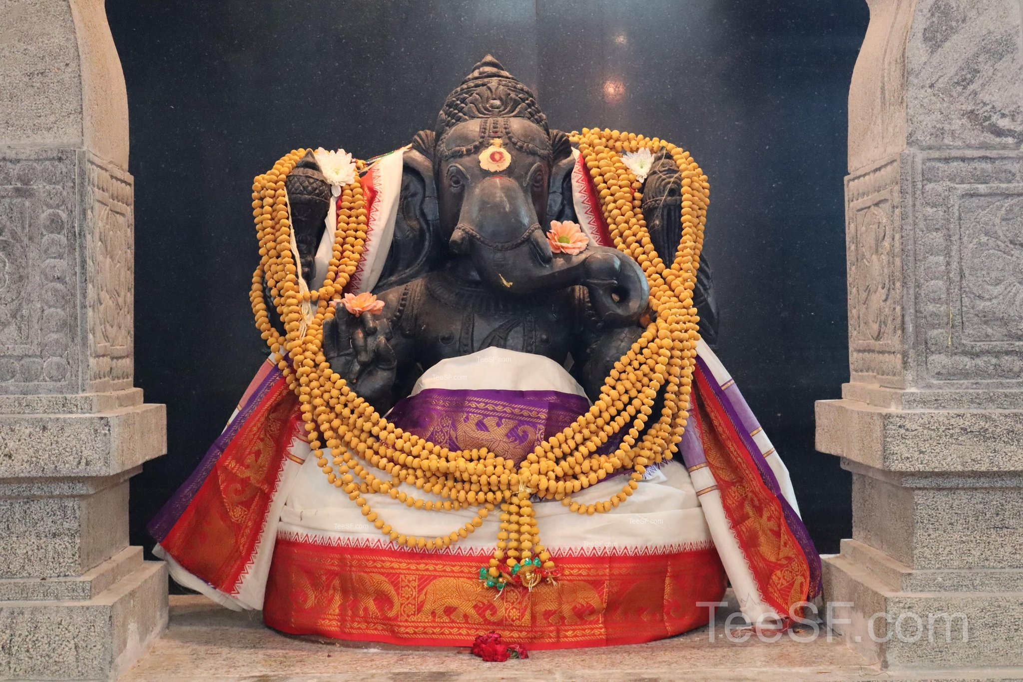 A Ganesha shrine framed by carved stone and gold decoration.